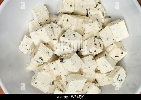 Il tofu cubess con erbe aromatiche in vaso bianco closeup Foto Stock