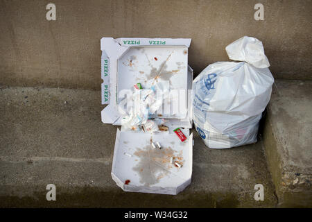 La Francia. Ad Arles. 2019. La spazzatura in strada - il sacchetto in plastica, vecchia scatola pizza e mozziconi di sigaretta. Foto Stock