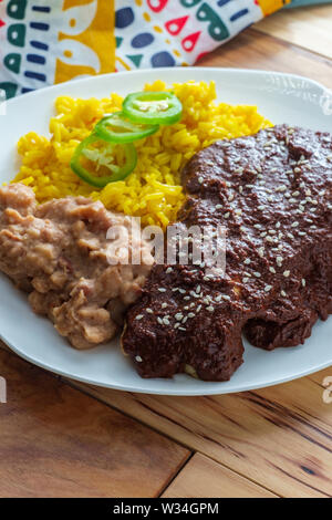 Mexican mole poblano pollo con riso e refried fagioli pinto Foto Stock