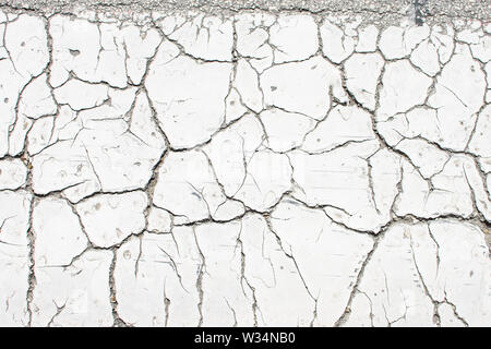 White vecchia vernice incrinata, incrinato dal calore del sole sulla superficie di calcestruzzo. Ottimo per la progettazione e la consistenza dello sfondo. Foto Stock