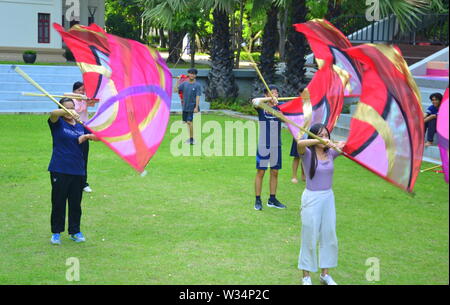 Giovani studenti in pratica la filatura di bandiera al di fuori sul prato all'università di Chulalongkorn nella zona centrale di Bangkok, Thailandia, Asia Foto Stock