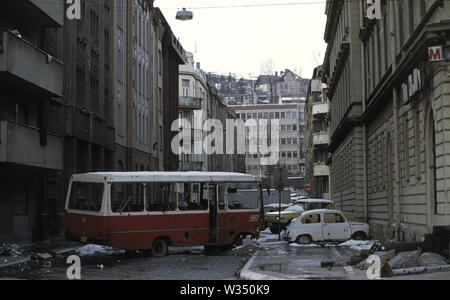 2 aprile 1993 durante l'assedio di Sarajevo: la vista nord lungo Kralja Tvrtka street. Un bus distrutto agisce come copertura da serbo-bosniaco cecchini che sono a poche centinaia di metri a sud. In fondo alla strada è l'ala ad ovest del Dr Abdulah Nakas General Hospital, localmente conosciuta come la 'città' o 'French' ospedale durante la guerra. Foto Stock