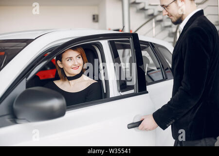 Eleganti e alla moda donna in un salone di auto Foto Stock