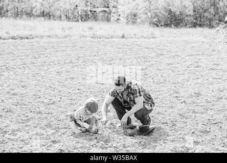 Piccolo bambino aiutare il padre in agricoltura. nuova vita. suoli e fertilizzanti. padre e figlio piantare fiori in massa. felice giornata della terra. Albero di famiglia. ricco terreno naturale. Eco farm. La giornata della terra. Avere successo. Foto Stock