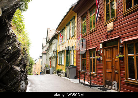 Le tradizionali case in legno dipinte di colori volano bandiere norvegesi nel centro storico di Bergen, Norvegia. Foto Stock