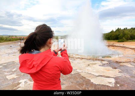 Islanda turistica prendendo le foto di geyser Strokkur. Donna visitare famose attrazioni turistiche e punti di interesse sul cerchio d'oro. Ragazza sulla vacanza escursioni natura Islandese. Foto Stock