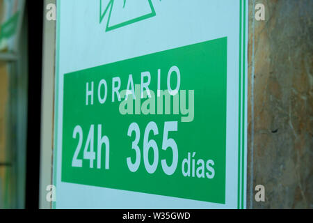 Sign in spagnolo al di fuori di una farmacia a Siviglia in Spagna che è aperto 24 ore al giorno, 365 giorni all'anno; sempre aperto, non chiudere mai. Foto Stock