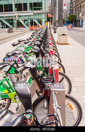 MONTREAL, Canada - 17 giugno 2018: La città di Bixi noleggio biciclette sono allineati in corrispondenza di uno dei numerosi sistemi automatizzati di stazioni docking downtown. Foto Stock