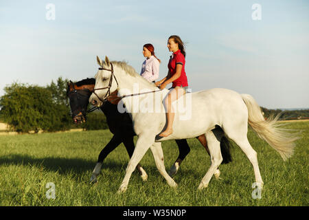 Due giovani ragazza a cavallo sulla passeggiata nel pomeriggio di estate Foto Stock