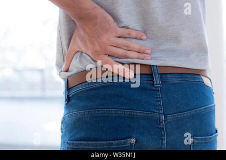 Uomo di toccare il suo indietro nel dolore. Foto Stock