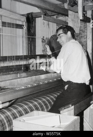 Anni '1960, storico, un uomo seduto, che usa un tradizionale telaio di tessitura, Scozia, Regno Unito. Questi telai erano interamente azionati da weaver, che utilizzava i pedali per spostare le filettature sui telai in legno. Foto Stock