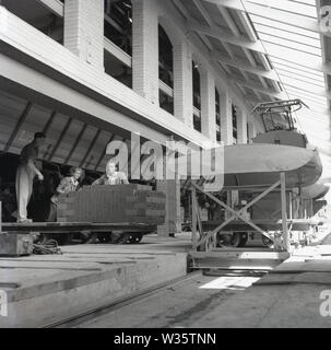 Anni '1950, storico, tre operai, due maschi e una femmina, spostando recentemente mattoni antincendio su un carrello presso la London Brick Company, Stewartby, Bedford, Inghilterra, Regno Unito. Foto Stock