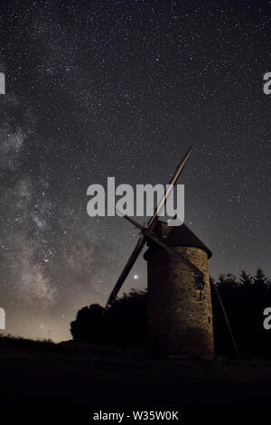 Un vecchio mulino a vento restaurato di notte davanti a uno sfondo di una notte stellata con la via lattea. Foto Stock