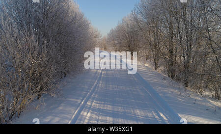 Vista aerea del paesaggio invernale con il trasporto su strada e gli alberi coperti di neve. Inverno in campagna Foto Stock