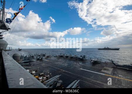 190711-N-PL543-1007 CORAL SEA (Luglio 11, 2019) della Marina distribuita portaerei USS Ronald Reagan (CVN 76) vele a fianco, da destra a sinistra, IL GOVERNO DEGLI STATI UNITI Marina di assalto anfibio nave USS Wasp (LHD 1), il Giappone marittimo Forza di Autodifesa elicottero destroyer JS Ise (DDH 182), e il Royal Australian Navy atterraggio elicottero dock HMAS Canberra (L 02) durante il talismano Sabre 2019. Talisman Sabre 2019 illustra la vicinanza dell'Australia e Stati Uniti alliance e la resistenza delle strutture militari del rapporto. È l'ottava iterazione di questo esercizio. (U.S. Navy foto di Foto Stock