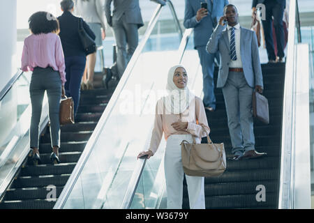 Diverse persone di business utilizzando le scale mobili in ufficio moderno Foto Stock