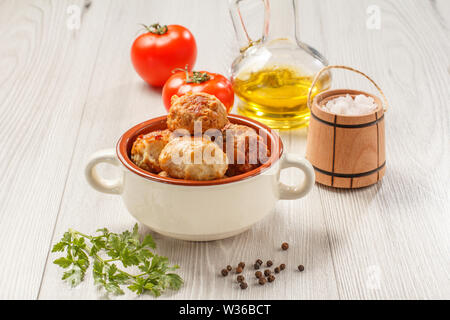 Fritte costolette di carne in ceramica Soup Bowl, pomodori rossi, bottiglia di vetro con olio di semi di girasole, sale in legno canna cantina e il ramo di prezzemolo fresco sul gra Foto Stock