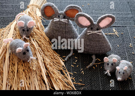 Gruppo di maglia fatti a mano mouse grigio su asciutto covone di piante di riso con sfondo nero, artigianato rat da filati così carino e bella e significativa per il regalo o Foto Stock