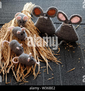 Gruppo di maglia fatti a mano mouse grigio su asciutto covone di piante di riso con sfondo nero, artigianato rat da filati così carino e bella e significativa per il regalo o Foto Stock