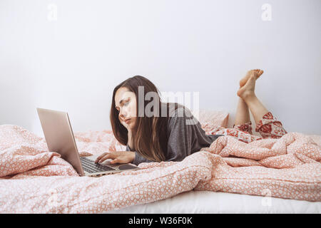 Triste o turbare ragazza utilizzando un computer portatile a letto. Foto Stock