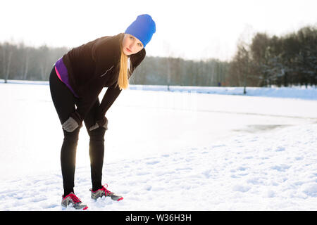 Giovane donna riposo dopo winter run Foto Stock