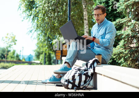 Occupato freelancer lavorando sul computer portatile mentre è seduto nel parco Foto Stock