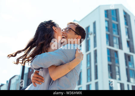 Sostegno amorevole marito sollevamento ricci la sua giovane moglie Foto Stock