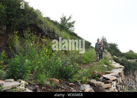 (190713) -- ZHANGZI, luglio 13, 2019 (Xinhua) -- Forest ranger il sig. egli Xiaohong(parte anteriore) e Lin Zhongkui patrol sul Monte Fajiu, 25 km a ovest di Zhangzi County, a nord della Cina di nella provincia di Shanxi, luglio 12, 2019. Vi è una foresta-patroller stazione sul Monte Fajiu dove la foresta di copertura è quasi il 90%. Il sig. egli Xiaohong è impegnata nella protezione della foresta per 34 anni da quando era 19. Insieme con i suoi colleghi, il sig. ha bisogno di pattuglia due volte dalla mattina presto alla sera per tutto l anno per assicurarsi che le foreste sono in buona situazione. Sotto la loro protezione, non vi è mai stata alcuna wil Foto Stock