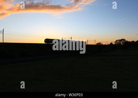 Nuova classe di CAF 195 treno di Arriva rampa settentrionale facendo una silhouette al tramonto sulla linea principale della costa occidentale mentre su un driver formazione gestita Foto Stock