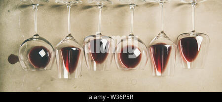 Flat-lay di vino rosso in bicchieri diversi su cemento grigio Sfondo, vista dall'alto. Bojole nouveau, wine bar, enoteca, degustazione concetto Foto Stock