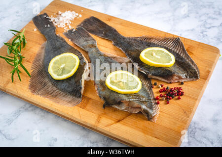 Non cotte fresche passera pianuzza Pesce con spezie sul pannello di legno Foto Stock