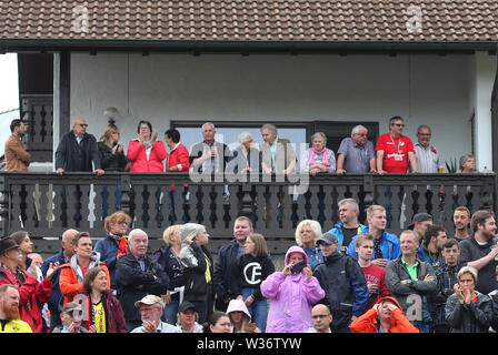 Hardheim, Germania. 12 Luglio, 2019. Gli spettatori seguono la partita allo stadio e dal balcone di un edificio residenziale. Credito: Karl-Josef Hildenbrand/dpa/Alamy Live News Foto Stock