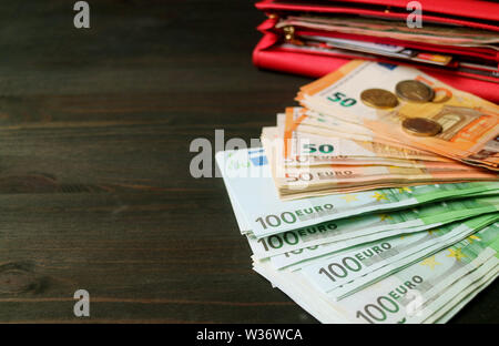 Closeup mazzetti di banconote in euro con sfocata monete e una apertura red wallet in background Foto Stock