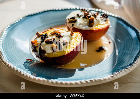 Pesche al forno con yogurt greco, noci tostate e miele / le pesche noci. Dessert organico. Foto Stock