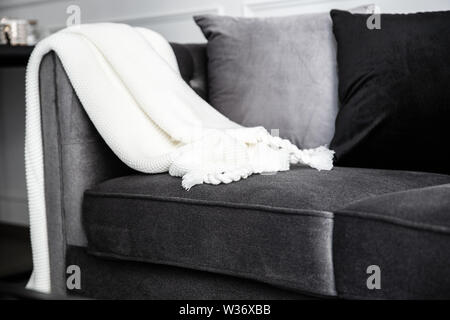 Soggiorno interno con con il grigio fablic divano, comodi cuscini, plaid e maglia whithe coperta. Decorazione moderna room interior design. Foto Stock
