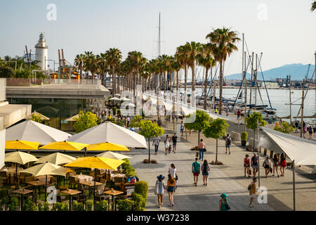 Malaga, Spagna - 23 giugno 2018. Le persone sono a piedi lungo il terrapieno (Paseo Del Muelle Dos Promenade) che si estende attraverso la porta sotto un costrutto Foto Stock