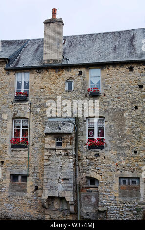 Il vecchio edificio in pietra, appartamenti, scatole di finestra, rosso dei gerani, Europa, Normandia; Bayeux; Francia; estate; verticale Foto Stock