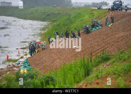 Yugan, la Cina della provincia di Jiangxi. 13 Luglio, 2019. Le persone organizzano dei sacchi di sabbia per rinforzare una diga in Jiangbu township di Yugan County, Cina orientale della provincia di Jiangxi, il 13 luglio 2019. Il livello delle acque del lago Poyang è al di sopra della linea di avvertimento a causa di una continua pioggia pesante. Credito: Hu Chenhuan/Xinhua/Alamy Live News Foto Stock