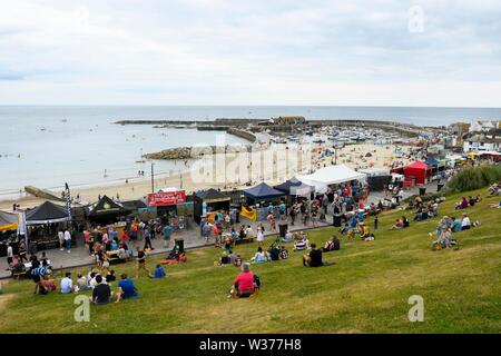 Lyme Regis, Dorset, Regno Unito. 13 luglio 2019. Regno Unito Meteo. I visitatori accorrono per un festival di cibo sopra la spiaggia come si divertono alla stazione balneare di Lyme Regis in Dorset in un caldo giorno nuvoloso. Credito Foto: Graham Hunt/Alamy Live News Foto Stock