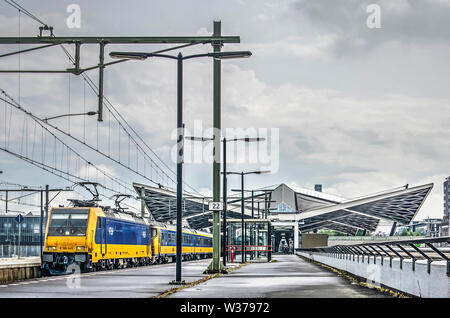 Tilburg, Paesi Bassi, 12 Luglio 2019: il giallo e il blu delle ferrovie olandesi treno intercity presso la prima piattaforma della stazione centrale con la characte Foto Stock