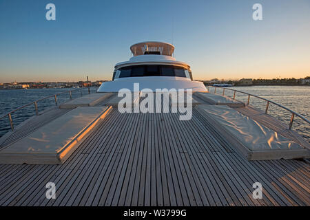 Vista sulla prua di una grande lussuoso yacht a motore sulla tropicale oceano aperto con lettini per prendere il sole al tramonto Foto Stock