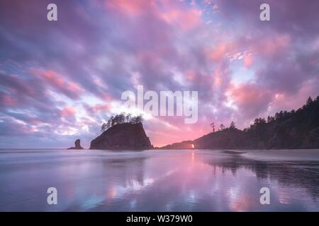Il tramonto a Cannon Beach con spettacolari nuvole sullo sfondo e un bel riflesso in acqua. Spettacolare paesaggio costiero con rocce panoramiche Foto Stock