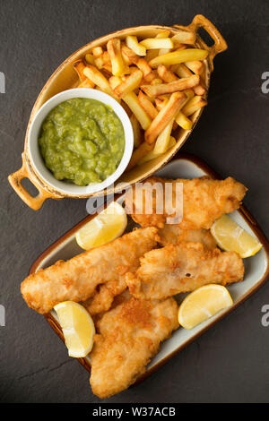 Filetti di fritte busbana francese, Trisopterus luscus, che sono state rivestite nella pastella e fritti in casa per fare un pesce e patatine cena. La Busbana francese Foto Stock