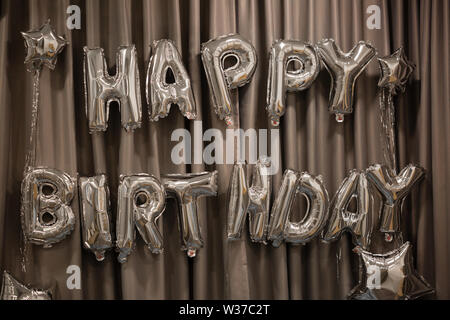 Lettere maiuscole buon compleanno da palloncini argentati Foto Stock