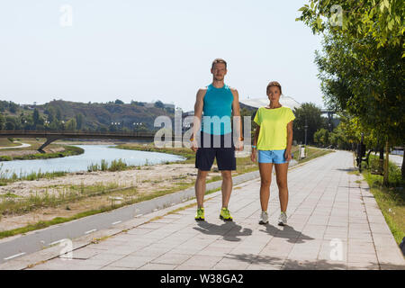 Colpo di giovane donna e uomo che corre attraverso il riverside via Foto Stock