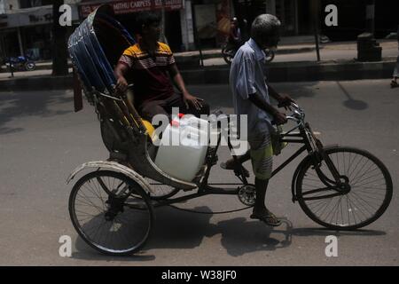 Luglio 14, 2019 - Dhaka, Bangladesh - un residente di carie contenitore di acqua in rickshaw come egli raccoglie acqua da uno dei nuovi ATM-sistema di erogatori di acqua installato nell'elefante area stradale. Il nuovo sistema, che utilizza una smart card che sono portare rilasciati ai residenti si propone di fornire un detergente e più conveniente per residenti urbani. Gli erogatori sono portare impostato attraverso una partnership con acqua danese engineering company Grundfos e governo attraverso WASA (approvvigionamento idrico e rete fognaria competente) dell'azienda. Il sistema ATM fornisce un litro di acqua potabile per 40 paisa (0,005$) per litro. (Credito Immagine: © MD Foto Stock