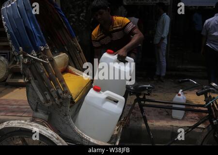 Luglio 14, 2019 - Dhaka, Bangladesh - Un residente si solleva il contenitore dell'acqua su rickshaw come egli raccoglie acqua da uno dei nuovi ATM-sistema di erogatori di acqua installato nell'elefante area stradale. Il nuovo sistema, che utilizza una smart card che sono portare rilasciati ai residenti si propone di fornire un detergente e più conveniente per residenti urbani. Gli erogatori sono portare impostato attraverso una partnership con acqua danese engineering company Grundfos e governo attraverso WASA (approvvigionamento idrico e rete fognaria competente) dell'azienda. Il sistema ATM fornisce un litro di acqua potabile per 40 paisa (0,005$) per litro. (Credito Immagine: © Foto Stock