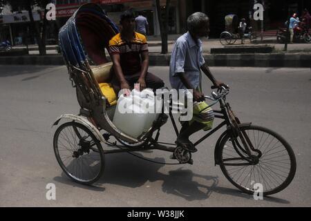 Dacca in Bangladesh, 14 luglio, 2019. Un residente di carie contenitore di acqua in rickshaw come egli raccoglie acqua da uno dei nuovi ATM-sistema di erogatori di acqua installato nell'elefante area stradale. Il nuovo sistema, che utilizza una smart card che sono portare rilasciati ai residenti si propone di fornire un detergente e più conveniente per residenti urbani. Gli erogatori sono portare impostato attraverso una partnership con acqua danese engineering company Grundfos e governo attraverso WASA (approvvigionamento idrico e rete fognaria competente) dell'azienda. Il sistema ATM fornisce un litro di acqua potabile per 40 paisa (0,005$) per litro. (Credito Immagine: © M Foto Stock