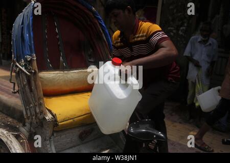 Dacca in Bangladesh, 14 luglio, 2019. Un residente si solleva il contenitore dell'acqua su rickshaw come egli raccoglie acqua da uno dei nuovi ATM-sistema di erogatori di acqua installato nell'elefante area stradale. Il nuovo sistema, che utilizza una smart card che sono portare rilasciati ai residenti si propone di fornire un detergente e più conveniente per residenti urbani. Gli erogatori sono portare impostato attraverso una partnership con acqua danese engineering company Grundfos e governo attraverso WASA (approvvigionamento idrico e rete fognaria competente) dell'azienda. Il sistema ATM fornisce un litro di acqua potabile per 40 paisa (0,005$) per litro. (Credito Immagine: © Foto Stock