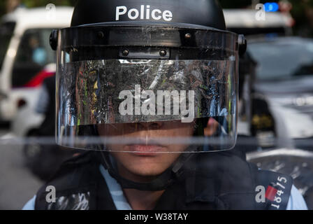 Un funzionario di polizia sta di guardia durante la protesta.Migliaia di manifestanti sono scesi in strada del Sheung Shui nel quartiere nord di Hong Kong in un anti-commercio parallelo di marzo. Alcuni manifestanti si scontrano con la polizia dopo il mese di marzo. Numero di manifestanti sono riportati per essere feriti. Foto Stock